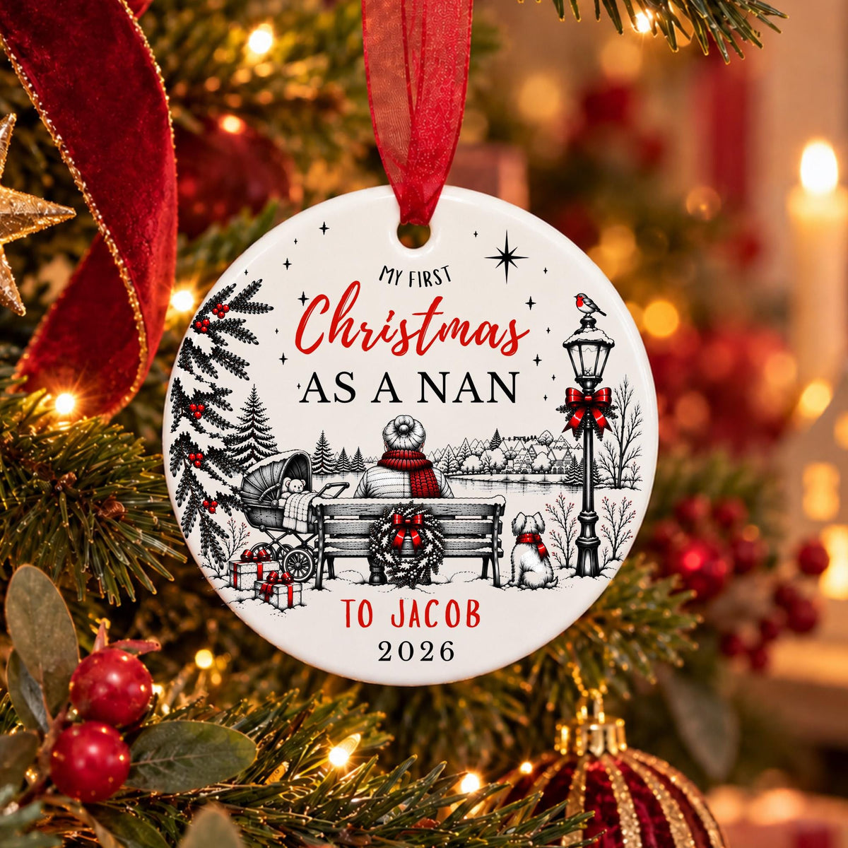 A personalized round Christmas ornament hanging on a decorated tree. The white ornament features black line art of a holiday scene with a bench, dog, lamp post, and red ribbon accents, along with the text 'MY FIRST Christmas AS A NAN TO JACOB 2026'.