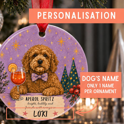 Personalized round Christmas ornament featuring a brown cockapoo dog illustration with a purple bow tie, set against a purple holiday background with stars, evergreen trees, and a drink. The ornament includes printed text fields for the dog's name and holiday phrase, with orange callout boxes explaining personalization.