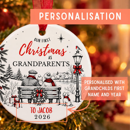 Personalized round Christmas ornament with a festive black-and-white holiday illustration and red text reading 'Our First Christmas as Grandparents' and 'To Jacob 2026,' shown with orange promotional callouts on a blurred holiday background.