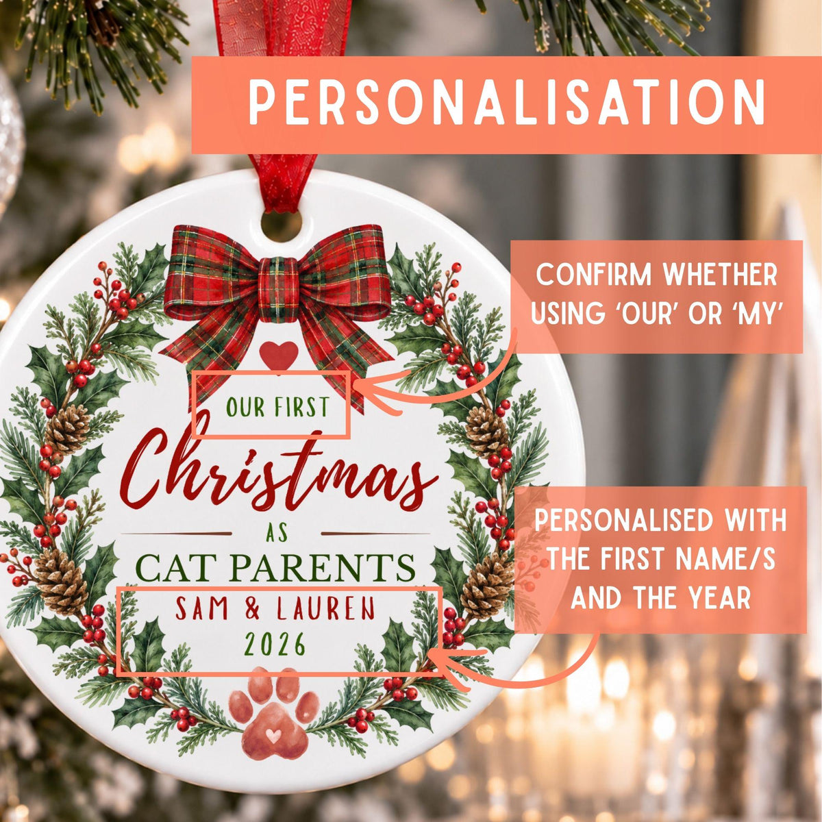 Personalized round Christmas ornament with a red ribbon hanger, featuring a festive wreath design with holly, pinecones, and red berries. The ornament includes customizable text such as 'Our First Christmas as Cat Parents' and sample names 'Sam & Lauren 2026'.