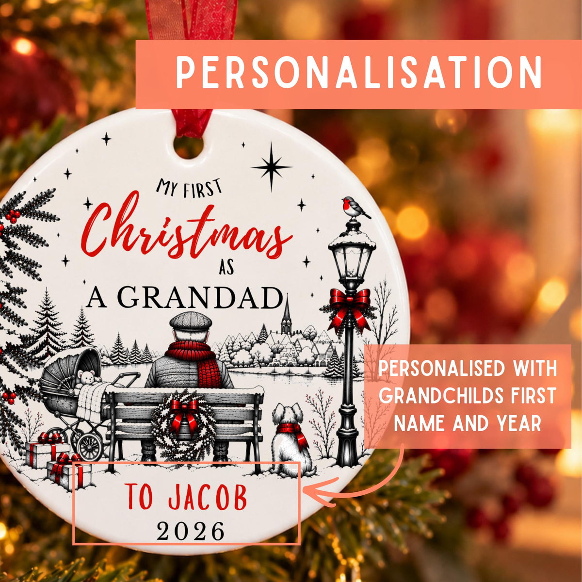 A personalized round Christmas ornament hanging in front of a blurred festive tree background. The ornament is white with red and black printed holiday artwork and text reading 'My First Christmas as a Grandad' and 'To Jacob 2026.