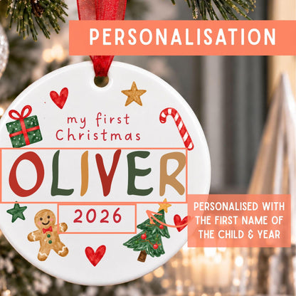 A round white ceramic Christmas ornament with red ribbon hanger, decorated with colorful holiday illustrations and the text 'my first Christmas OLIVER 2026'. The image includes promotional text overlays explaining personalization options, with a blurred festive background.