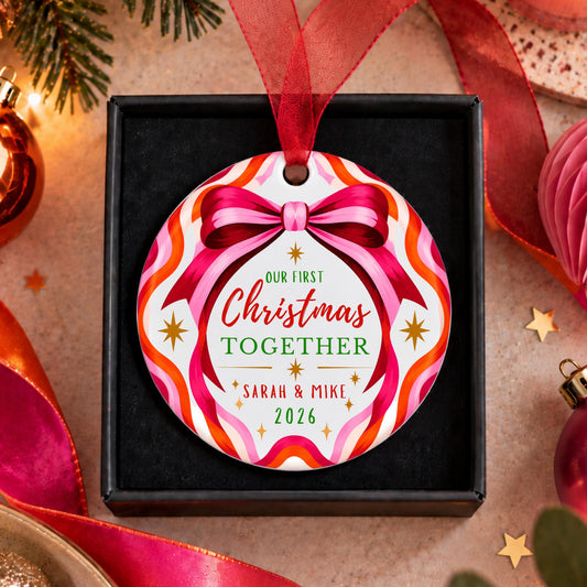 A personalized round Christmas ornament displayed in a black gift box, featuring a colorful wavy border and a red ribbon bow with the text 'Our First Christmas Together Sarah & Mike 2026'.