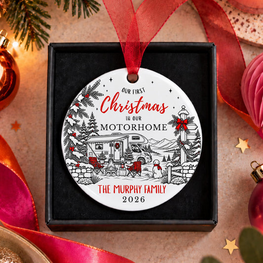 A personalized round Christmas ornament displayed in a black gift box, featuring a winter camping scene with red ribbon and red text reading 'Our First Christmas in our Motorhome The Murphy Family 2026'.