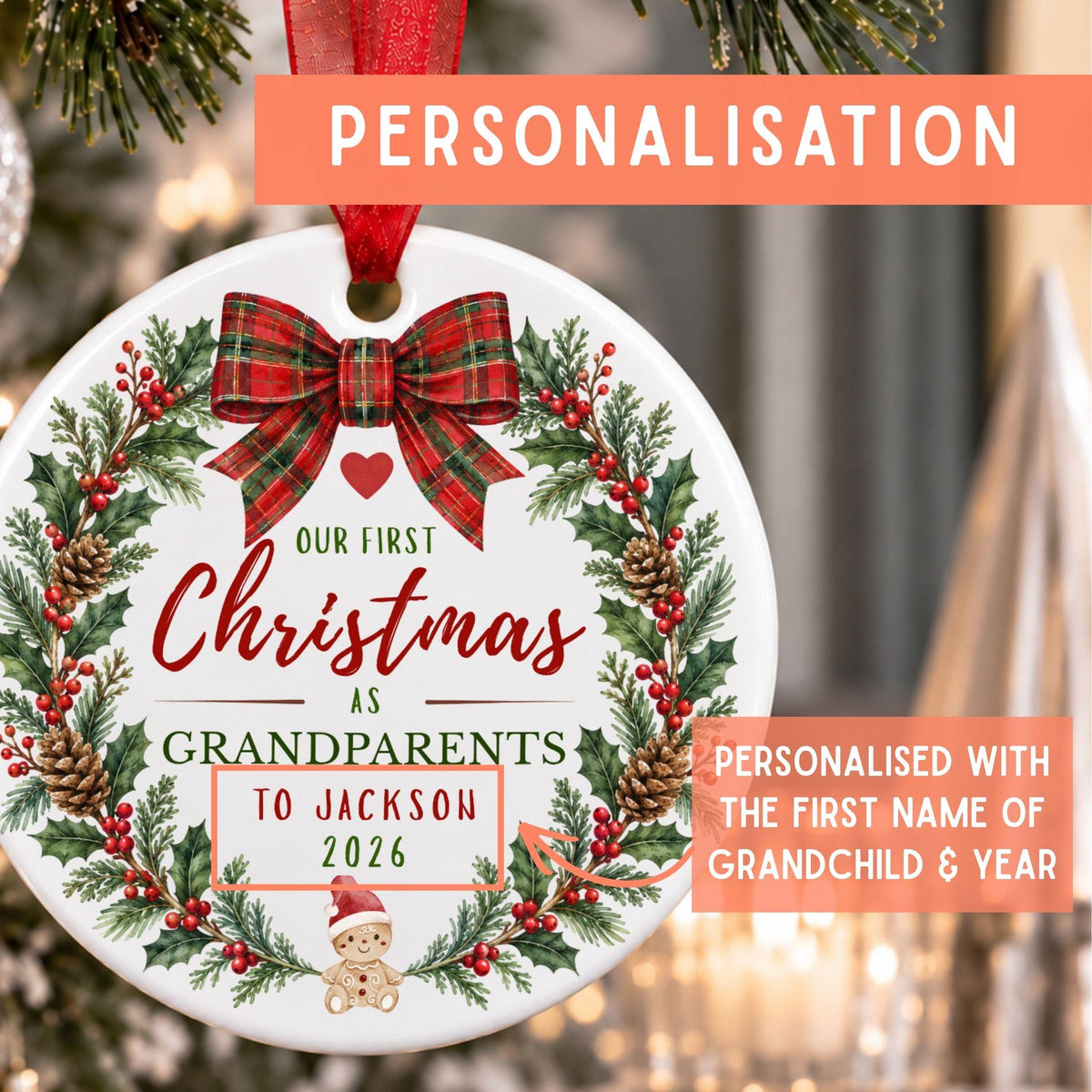 Personalized round Christmas ornament hanging on a decorated tree, featuring a red ribbon, green holly wreath, pinecones, red berries, and custom text reading 'Our First Christmas As Grandparents To Jackson 2026' with a small teddy bear illustration. Orange text banners highlight personalization.