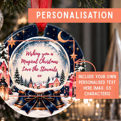Personalized round Christmas ornament mockup hanging on a tree, with a red ribbon loop, a dark navy night-sky scene, snowy village houses, stars, and a large glass snow globe center containing custom red text. Orange overlay text says PERSONALISATION and includes custom text area.