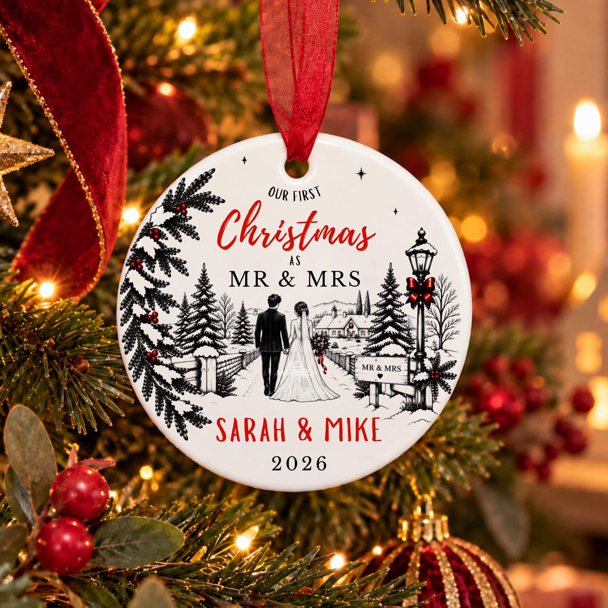 A personalized round Christmas ornament hanging on a decorated tree. The white ornament features a black-and-white winter wedding scene with a bride and groom walking, red script text reading 'Our First Christmas as Mr & Mrs', and red personalized names 'Sarah & Mike' with the year '2026'.