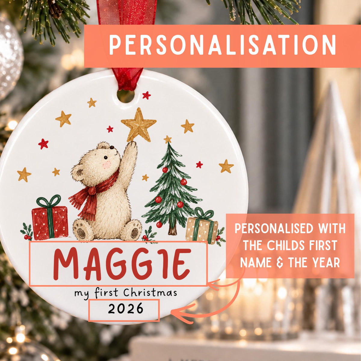 Personalized round ceramic Christmas ornament featuring a teddy bear, tree, gifts, and stars, with the name MAGGIE and year 2026, shown hanging in front of a blurred Christmas tree. Text overlays explain personalization.