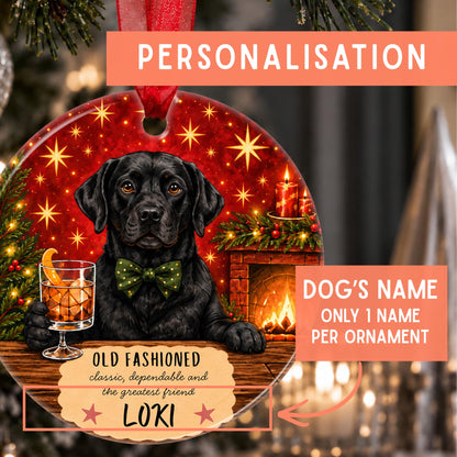 Personalized Christmas ornament featuring a black Labrador dog with a green bow tie, set against a festive holiday background with a fireplace, candles, and stars. The ornament includes customizable text fields for the dog's name and a red hanging ribbon.